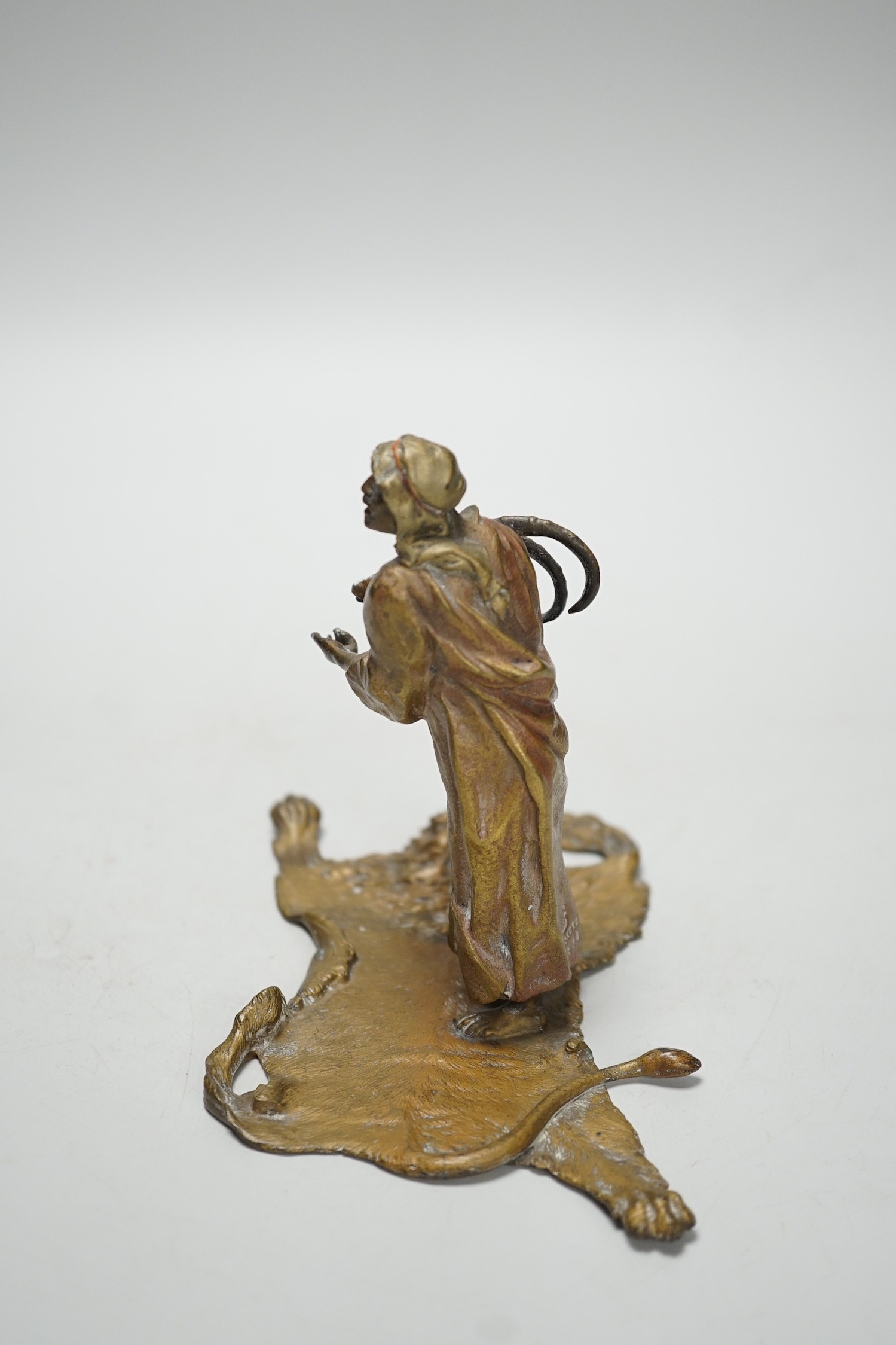 An Austrian cold painted bronze model of a Bedouin trader, depicted holding an Ibex head, standing on a lion skin, after Franz Bergman. 12cm tall